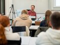 Veranstaltungsbericht Ein Dozent sitzt in einem Seminarraum und spricht mit den Anwesenden.