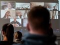Veranstaltungsbericht Leinwand mit einer Videokonferenz und zahlreichen Teilnehmenden.