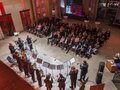 Blick von oben auf die Bühne, auf der die Musiker spielen, und auf das Publikum, das davor sitzt.