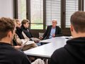 Veranstaltungsbericht Einer der Referenten sitzt mit den Teilnehmenden zusammen und tauscht sich aus.