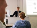 Veranstaltungsbericht Ein junger Mann steht während der Veranstaltung auf der Bühne und hält einen Vortrag.